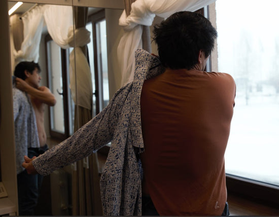 Back view putting on a shirt over the LESPIRANT LCut in Minsk looking outside the window